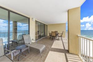 a balcony with chairs and tables and the ocean at Summer House 1105A in Orange Beach