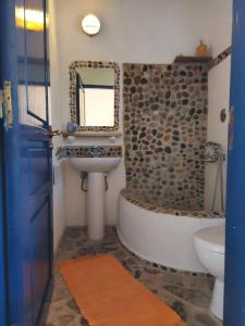 ein Badezimmer mit einem Waschbecken, einer Badewanne und einem WC in der Unterkunft Arancio independent room in Ecovilla on the beach in Apolakkiá
