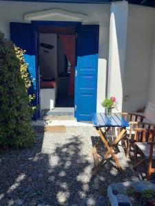 a blue door with a table in front of a house at Arancio independent room in Ecovilla on the beach in Apolakkiá