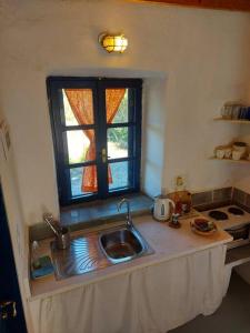 a kitchen with a sink and a window at Arancio independent room in Ecovilla on the beach in Apolakkiá