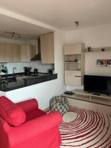 ein Wohnzimmer mit einem roten Sofa und einer Küche in der Unterkunft 2 Bedroom Apartment Condado de Alhama in Alhama de Murcia