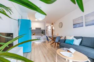 een woonkamer met een blauwe bank en een tafel bij Apartamento con terraza y vistas al canal by InsideHome in Empuriabrava