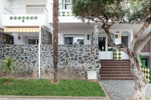 een huis met een stenen muur en een boom bij Apartamento con terraza y vistas al canal by InsideHome in Empuriabrava