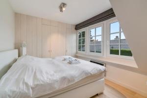 Habitación blanca con cama y ventana en Luxe familievilla voor 9pers met zee en tuinzicht, en Koksijde