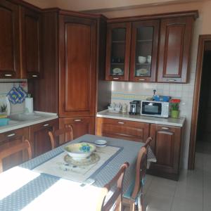 a kitchen with wooden cabinets and a table and a microwave at La Playa di Ponente in Cagliari
