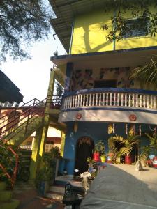 een geel en blauw huis met een balkon bij Advait Holiday Home in Nagaon
