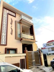 a house with a balcony and a car parked in front of it at A radiant villa on Ganges with modern amenities in Rishīkesh