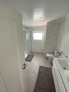 a white bathroom with a toilet and a window at Villa Tranquila, Playa del Duque in Adeje