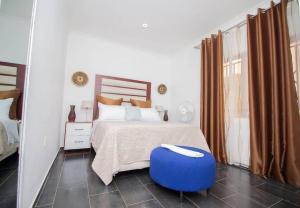 a bedroom with a bed with a blue ottoman at Banjii's Cottage in Lusaka