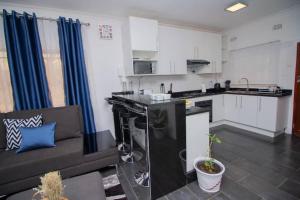 a kitchen and living room with a couch in a room at Banjii's Cottage in Lusaka