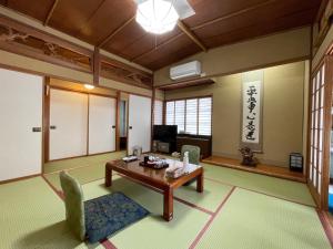 a living room with a table and chairs and a television at Sakaenoyu Ryokan in Matsumoto