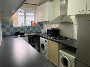 a kitchen with a sink and a stove top oven at Wembley Homes Serviced Apartment, 25mins to Central London in Wembley