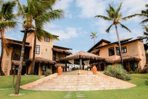 a house with palm trees in front of it at Anauí Pousada in Porto De Galinhas