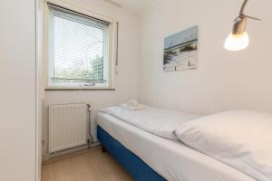 una piccola camera da letto con un letto e una finestra di Welcome in - Koekoeksbloemwei 90, Kortgene a Kortgene