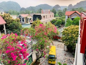 a yellow truck driving down a street with pink flowers at Elizabeth Hotel Tam Coc in Ninh Binh