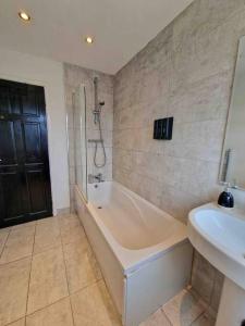 a bathroom with a bath tub and a sink at Stunning Gem detached with drive in High Hazels