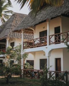 a large white building with a thatch roof at Blue Oyster Hotel in Jambiani