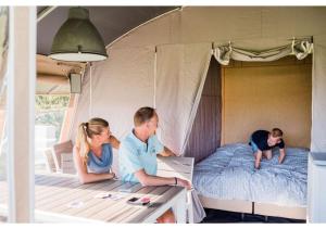 eine Gruppe von Personen, die in einem Zelt auf einem Bett sitzen in der Unterkunft Country Camp camping Südeifel in Irrel