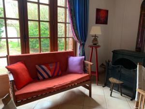 a living room with a red couch with colorful pillows at La Villa Flore in Saint-Jouin-Bruneval