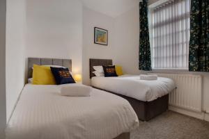 um quarto com 2 camas com almofadas amarelas e azuis em Beautiful Cottage in Wolsingham, Perfect for families! Sleeps 6 em Bishop Auckland