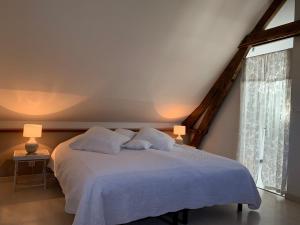 una camera con un letto bianco con due cuscini di La Villa Flore a Saint-Jouin-Bruneval