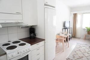 a white kitchen with a stove and a table at Lovely studio in Leppävaara in Espoo