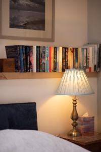una lámpara en una mesa junto a un estante con libros en Rosehill Barn -a tranquil rural barn conversion, en Barnstaple