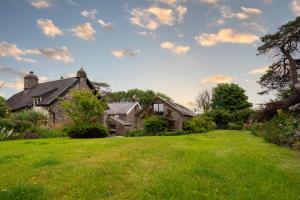 ein altes Steinhaus mit einem grasbewachsenen Hof in der Unterkunft Rosehill Barn -a tranquil rural barn conversion in Barnstaple