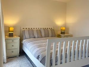 Cottage 170 - Roundstone في راوندستون: غرفة نوم مع سرير ابيض وجلستين نوم