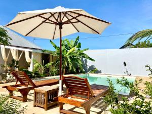 patio z 2 krzesłami i parasolem przy basenie w obiekcie Maisha Villa Nungwi w mieście Banda Kuu