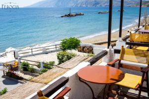 een balkon met een tafel en stoelen en een strand bij Ferogia in Skiros