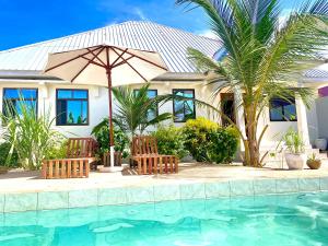 ein Haus mit zwei Stühlen und einem Sonnenschirm neben einem Pool in der Unterkunft Maisha Villa Nungwi in Banda Kuu