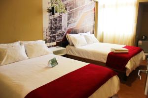 a hotel room with two beds with a picture on the wall at Terra Suites Ecogreen in Tacna