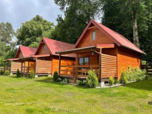 a large wooden cabin with a red roof at Chaty Mazur w Wierzbie in Ruciane-Nida