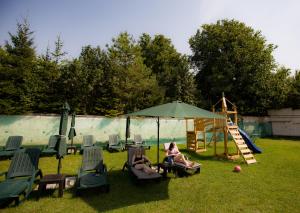 two women sitting in chairs under an umbrella next to a playground at Casa Moroeni in Moroeni