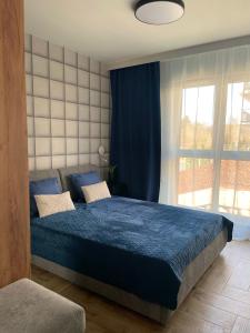 a bedroom with a blue bed and a window at Apartament I Młyny Gdańskie blisko centrum in Gdańsk