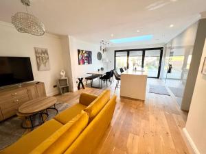 a living room with a yellow couch and a kitchen at Comfortable 3 Bedroom House with Garden and Parking – Sleeps up to 6 in Catford
