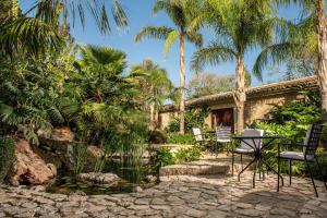 a patio with a table and chairs and palm trees at Castell Son Claret - The Leading Hotels of the World in Capdellá