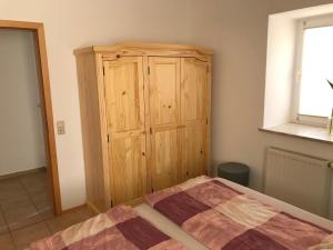 - une chambre avec une armoire en bois et un lit dans l'établissement Ferienwohnung Familie Nahrstedt Erdgeschoß, à Löbau
