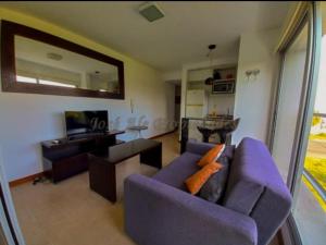 a living room with a purple couch and a television at Rambla Sacramento - Paz frente al Río in Colonia del Sacramento