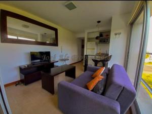 sala de estar con sofá púrpura y TV en Rambla Sacramento - Paz frente al Río, en Colonia del Sacramento