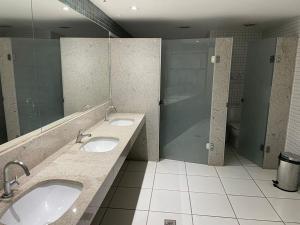 a public bathroom with two sinks and a shower at Kit perfeita no Park Sul in Brasilia