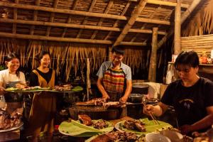 een groep mensen die rond een tafel met eten staan bij Puluong homestay1holiday in Pu Luong