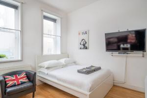 a white room with a bed and a tv on a wall at Soho Apartment Sleeps 4, Covent Garden & Leicester Square in London