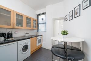 a kitchen with a table and a sink and a washing machine at Soho Apartment Sleeps 4, Covent Garden & Leicester Square in London