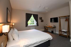 a bedroom with a large white bed and a desk at Wheatsheaf, Baslow by Marston's Inns in Baslow