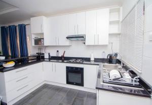 a kitchen with white cabinets and a sink at Banjii's Cottage in Lusaka