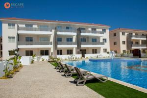 a hotel with a swimming pool and chairs in front of a building at Sweet Retreat in Paralimni