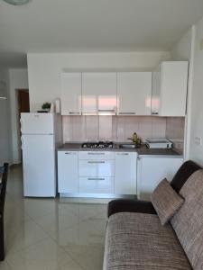 a white kitchen with white cabinets and a couch at Apartments Ivan in Povljana