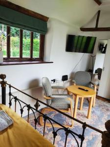 a living room with a tv and a table and chairs at The Retreat in Tibenham
